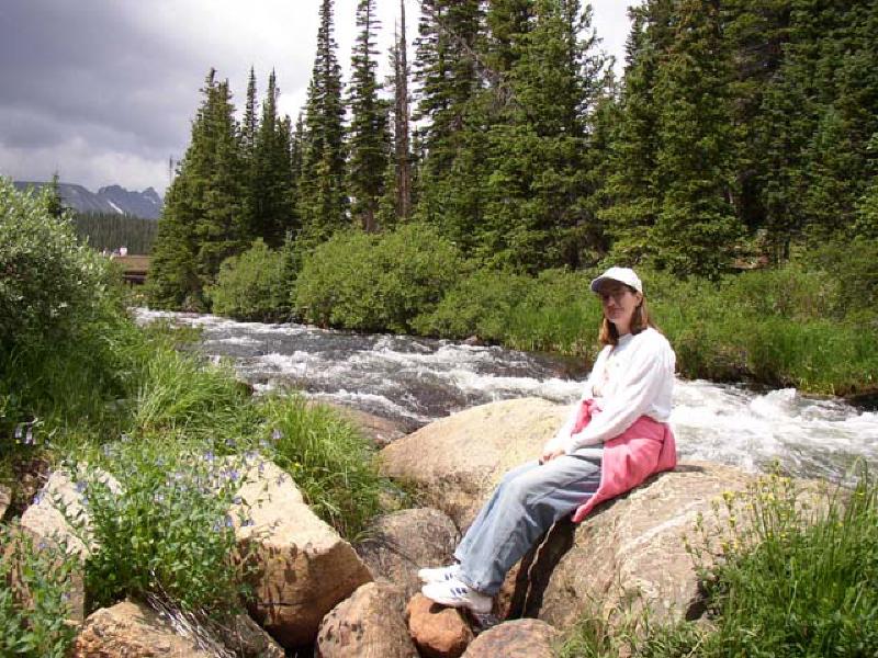 Marla enjoys the beautiful scenery as she rests near the mountain stream.