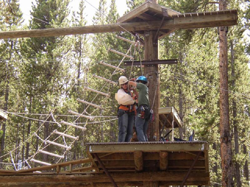 Eric Marchese helps Marla tie in to the zip line, which is a free-fall ride off the ropes course,down the cable on a pulley.