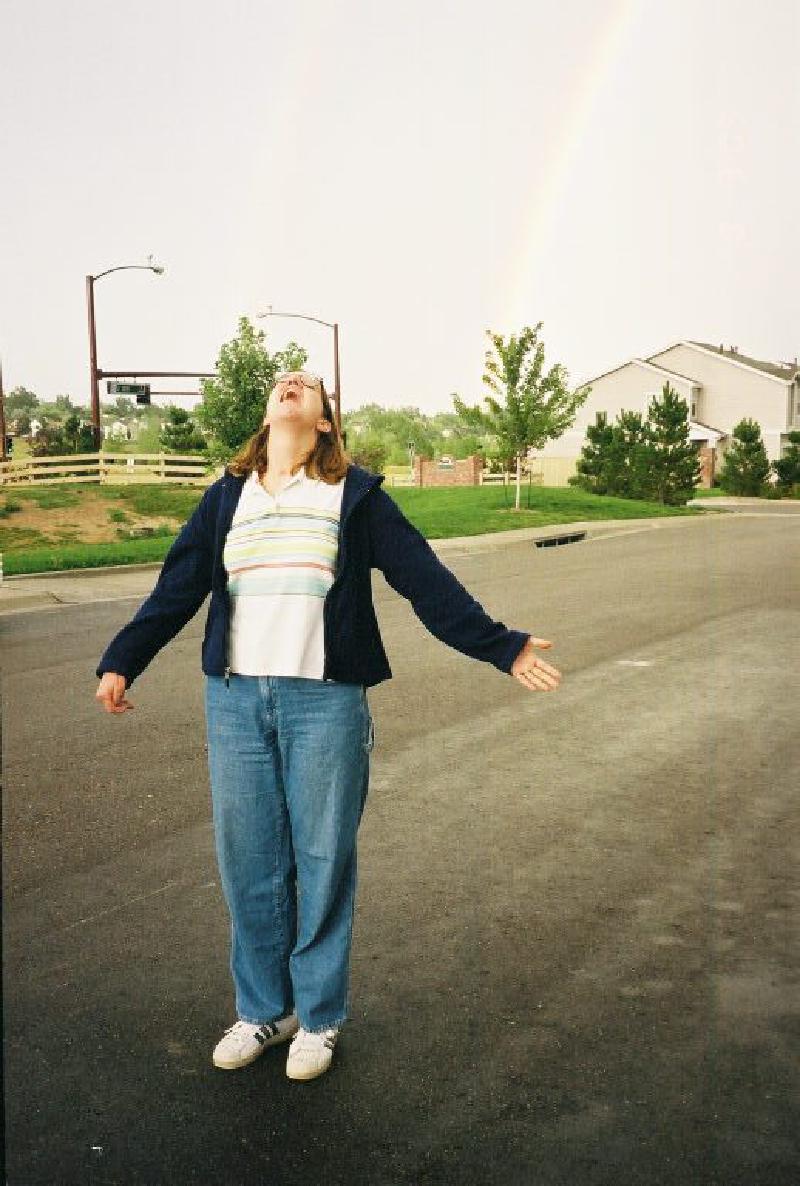 Marla enjoying the fresh air and rainbow following a summer storm outside her house.