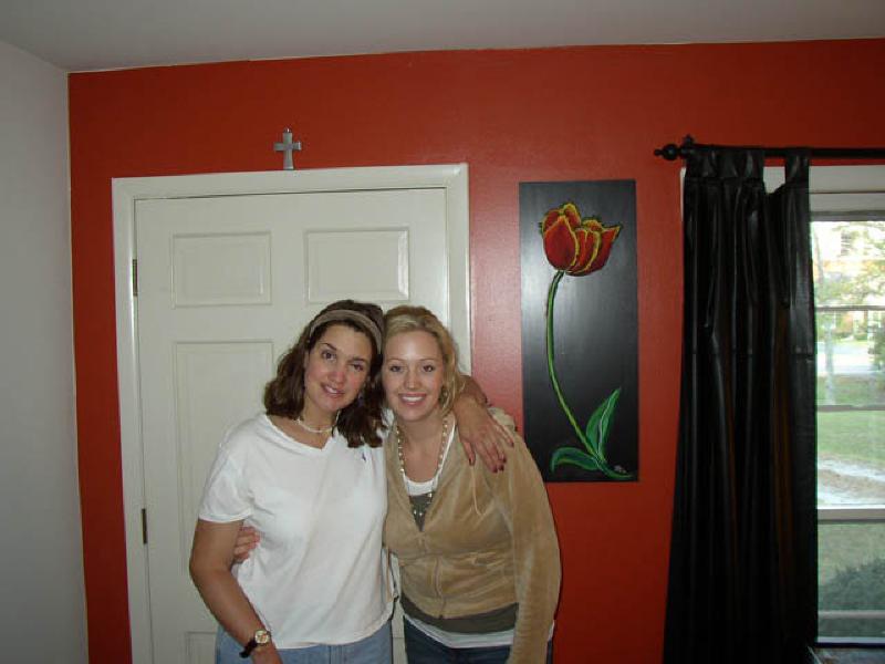 Marla and Nicole share a hug in Nicole's living room. A talented artist, Nicole painted the picture of the flower behind her and Marla!