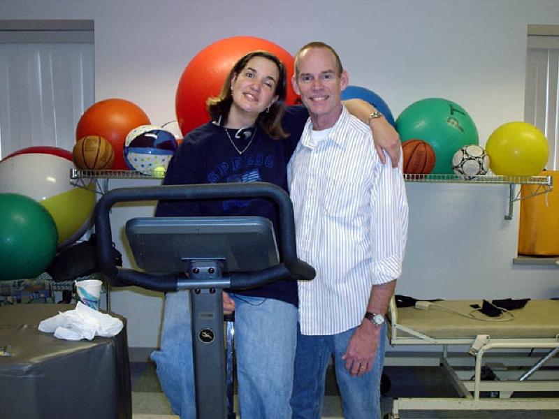 Dan Gibson, a physical therapy assistant at Craig Hospital, says hello to Marla while she works on the exercise bicycle. Dan just returned to work after undergoing back surgery.