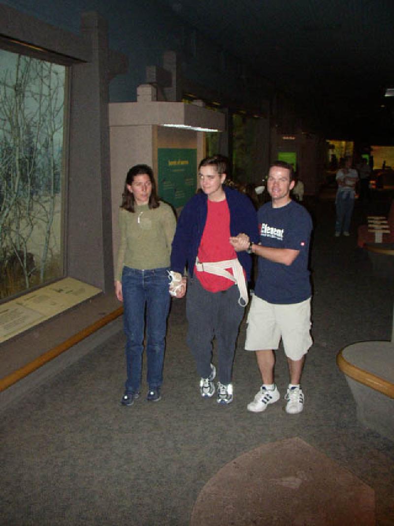 Marla walking with Heather, her speech therapist, and Rob, while strolling through the wildlife gallery at the Denver Museum of Nature and Science.